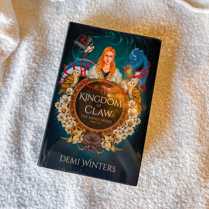 Book titled 'Kingdom of Claw' by Demi Winters on a textured white surface