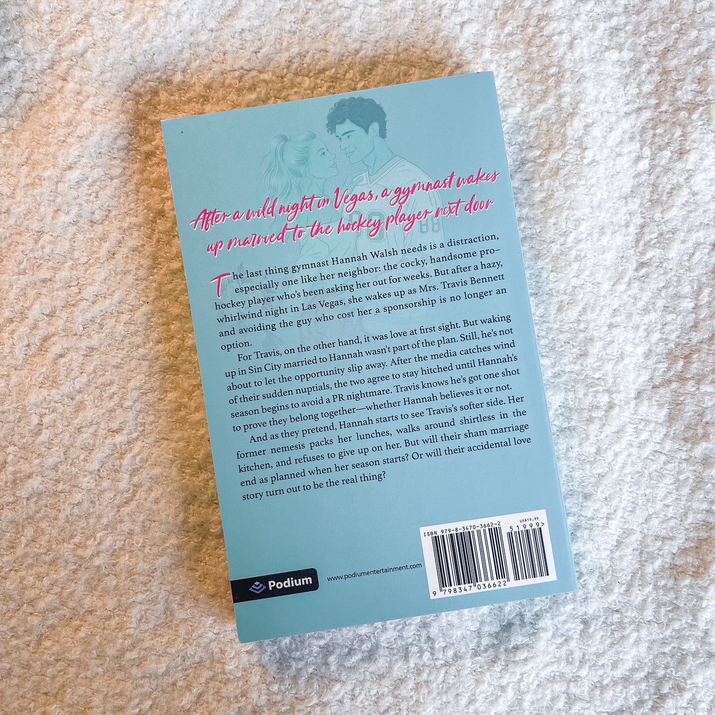 The back cover of a Podium book, featuring a light blue background with pink and black text, photographed flat on a textured beige stone surface.