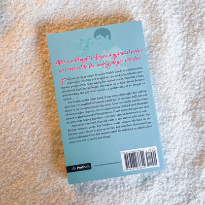 The back cover of a Podium book, featuring a light blue background with pink and black text, photographed flat on a textured beige stone surface.