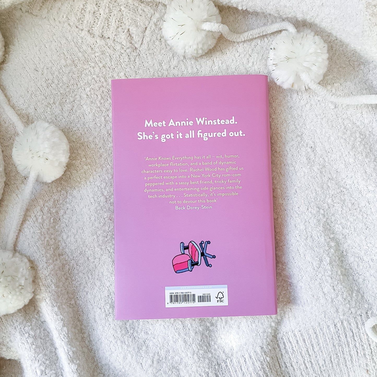 Pink book cover with text and a logo on a textured white surface
