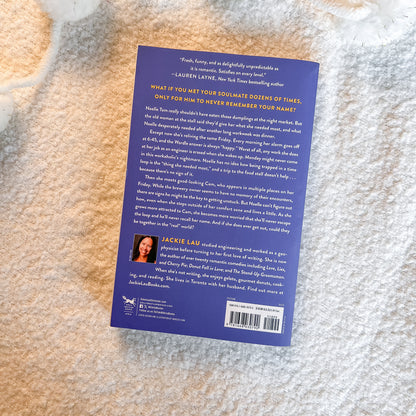 The back cover of the book, photographed flat on a textured white faux fur surface. The cover is a deep navy blue with white text and a small author portrait photo in the lower left.