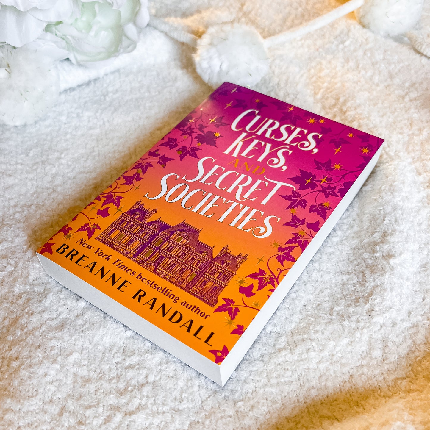 Book titled 'Curses, Keys, and Secret Societies' by Breanne Randall on a soft white surface.