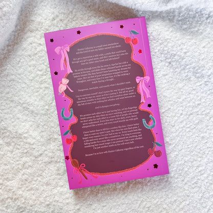 A pink printed book with a decorative border and paragraphs of text, placed on a soft white textured blanket.