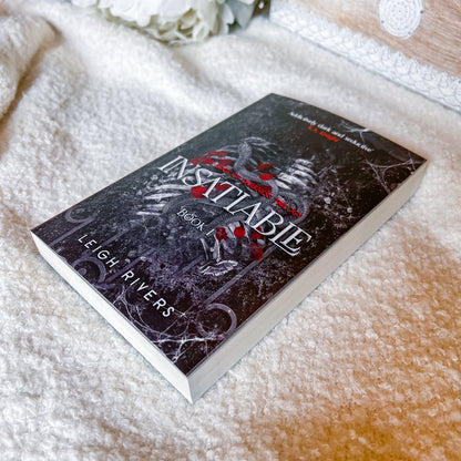 Book titled 'Insatiable' by Leigh Rivers on a textured surface