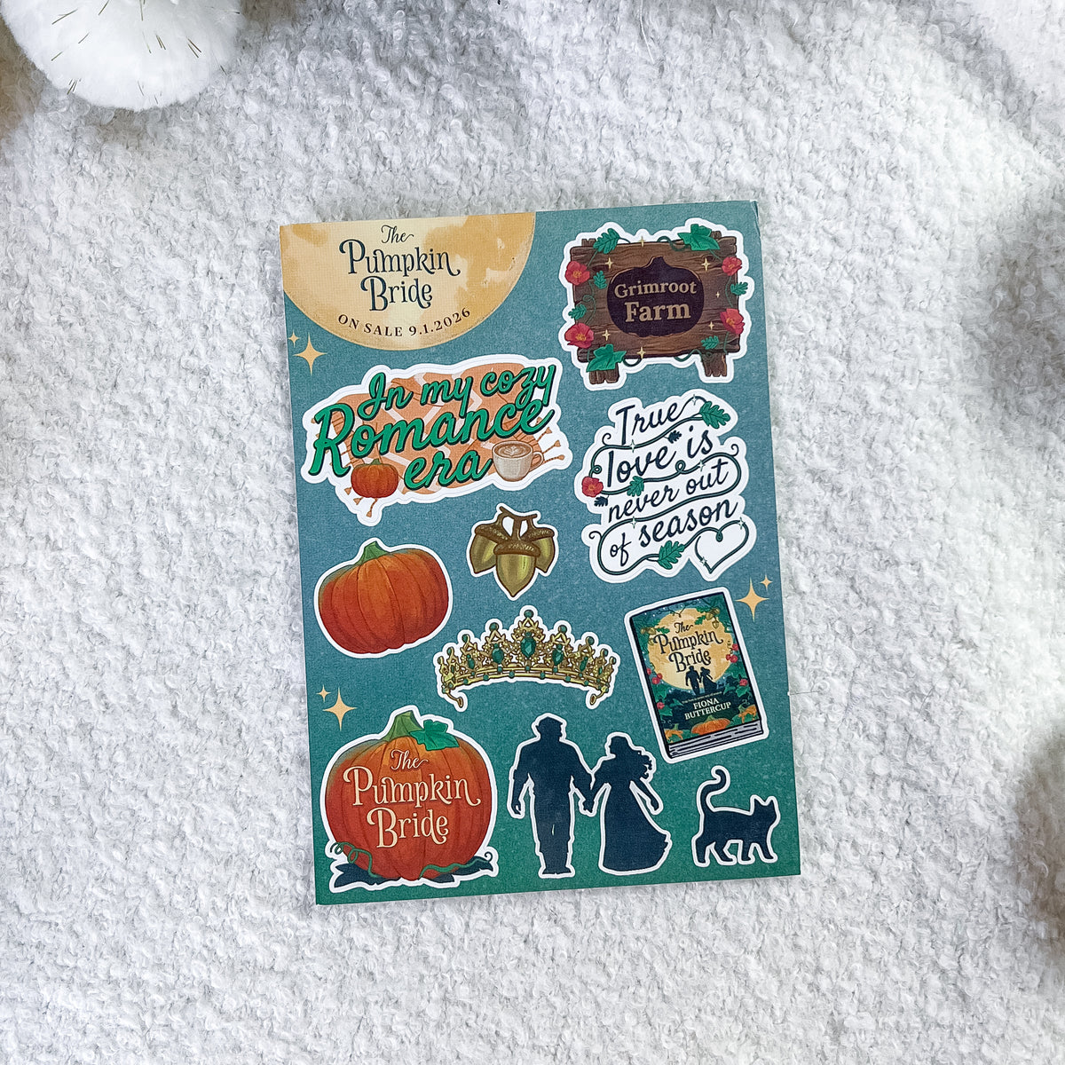 A sheet of decorative stickers from 'The Pumpkin Bride' journaling kit, displayed flat on a white textured fabric background. The stickers feature autumn-themed designs including pumpkins, a crown, silhouettes of a couple and cat, and quotes.