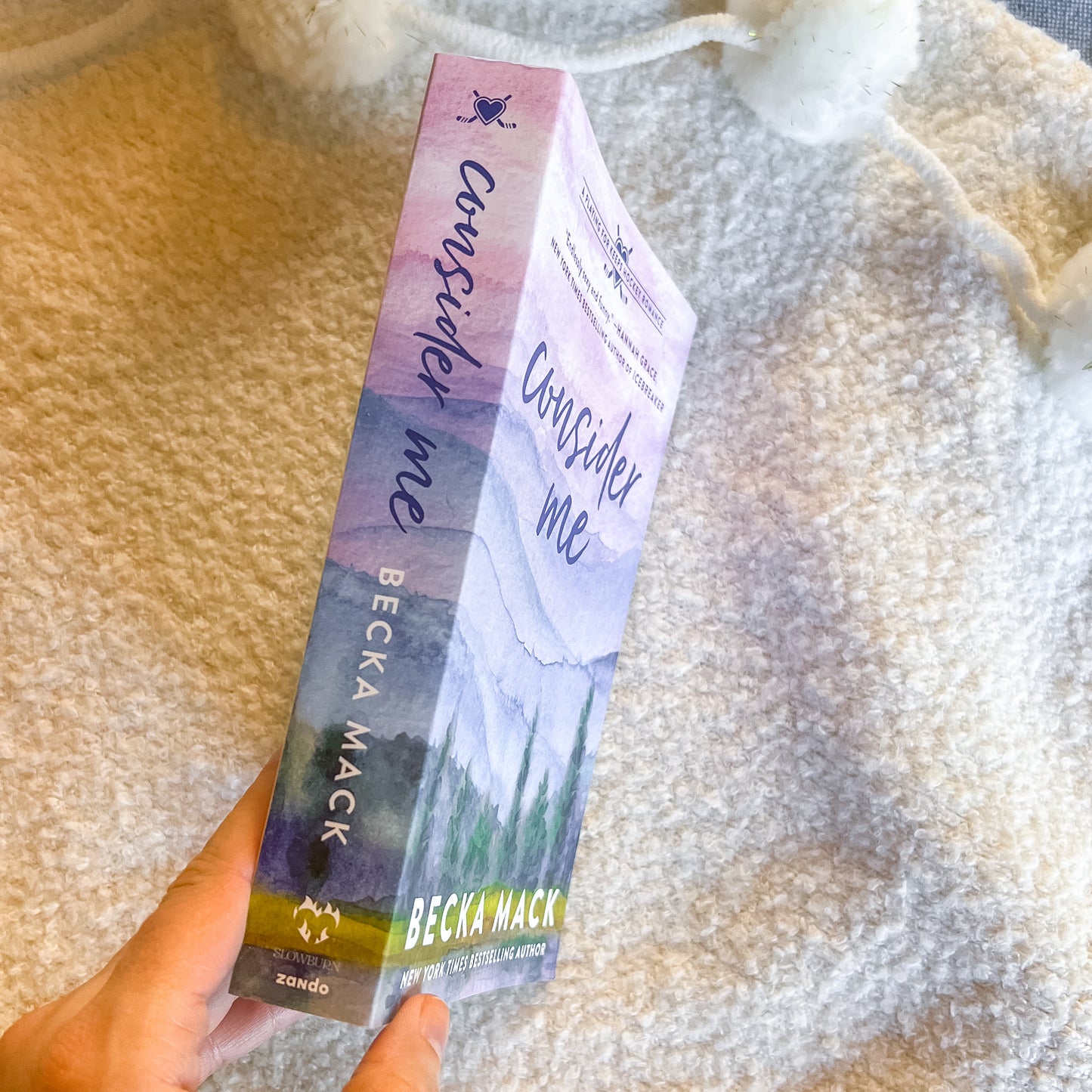 Book titled 'Consider Me' by Becka Mack held against a textured beige background