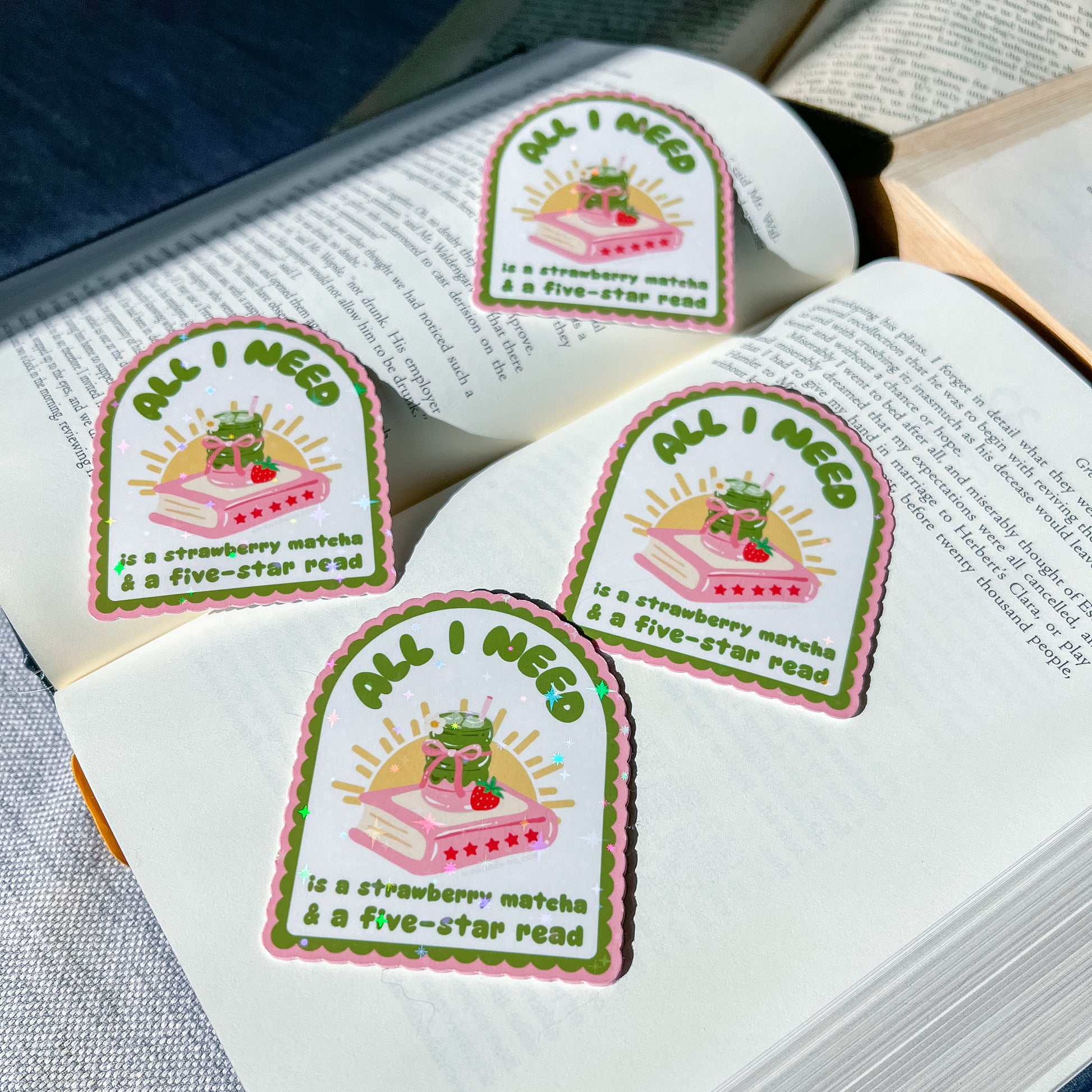 Four 'All I Need is a Strawberry Matcha & Five-Star Read' stickers on an open book.