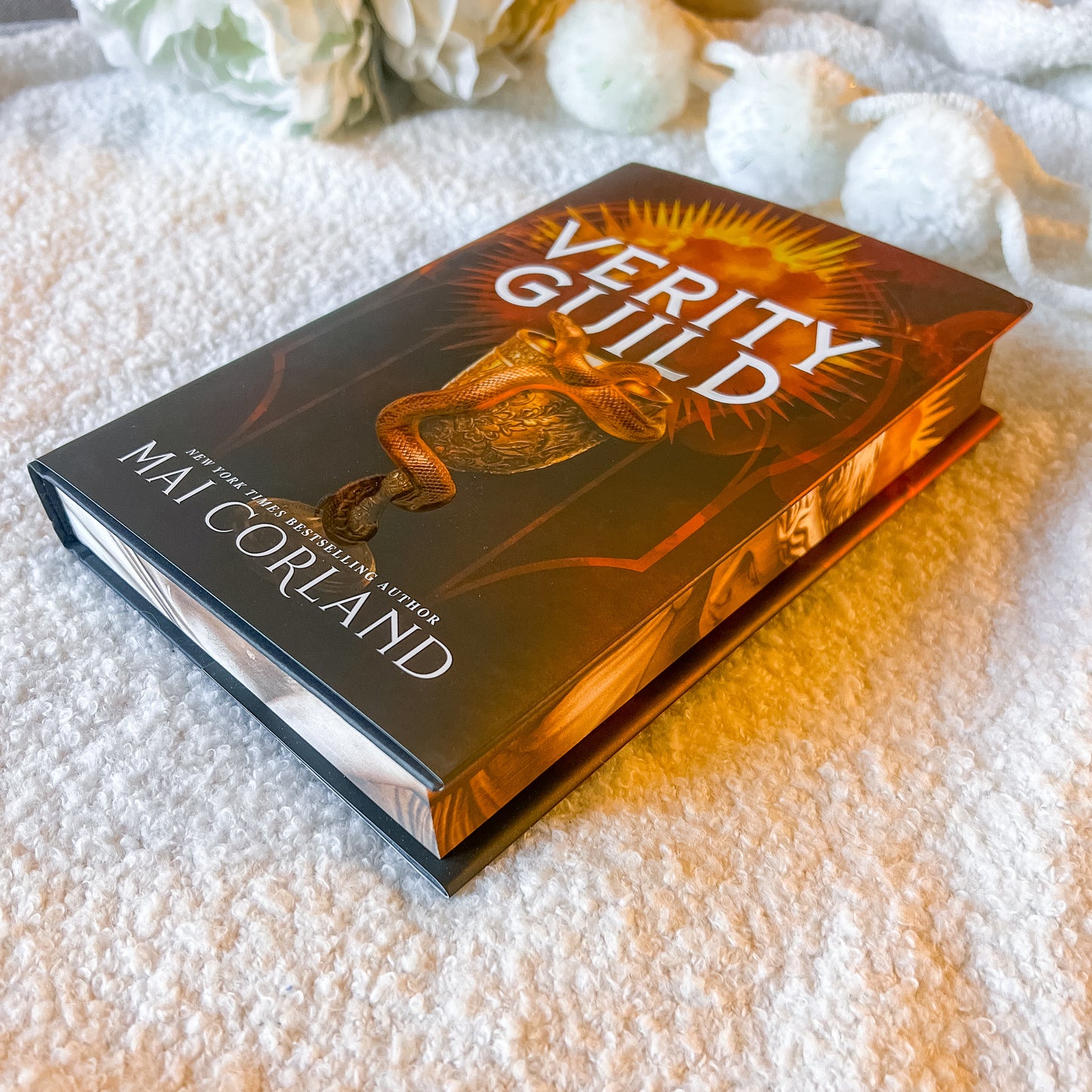 Book titled 'Verity Guild' by Mai Corland on a textured surface with decorative elements.