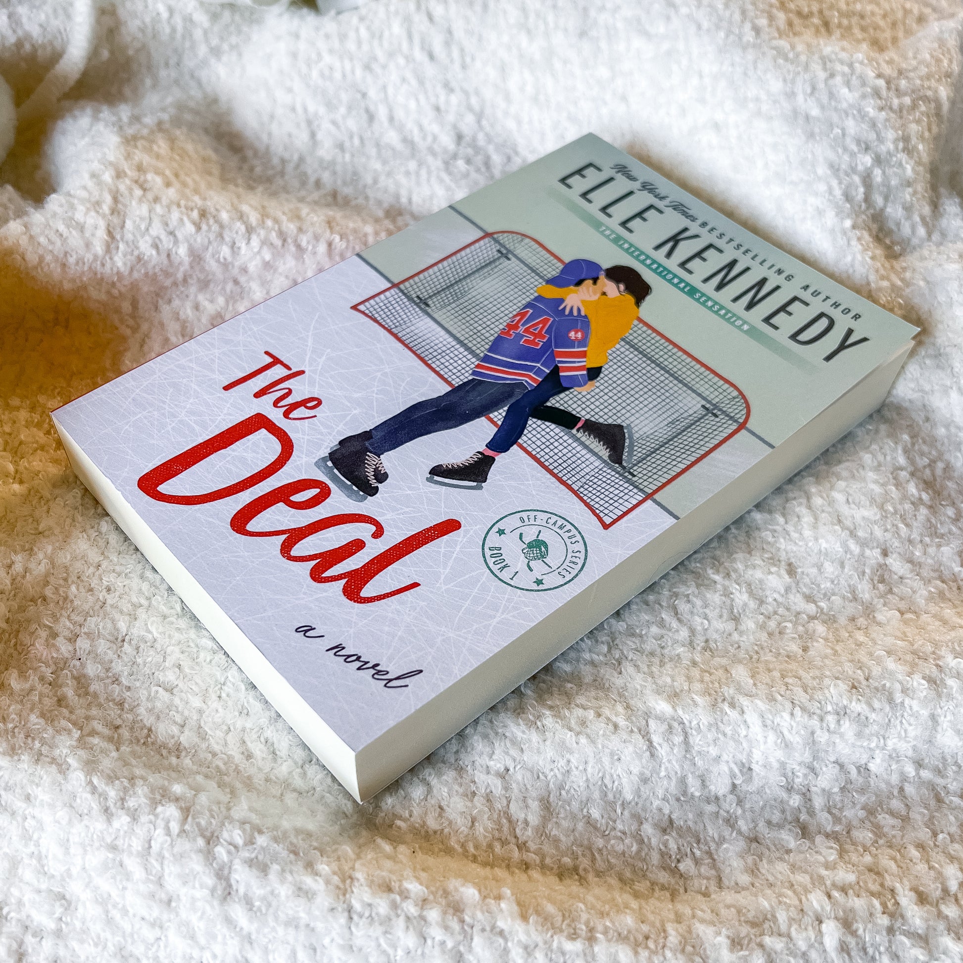 Book titled 'The Deal' by Elle Kennedy on a textured surface