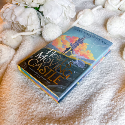 Book titled 'Howl's Moving Castle' by Diana Wynne Jones on a textured surface with flowers.