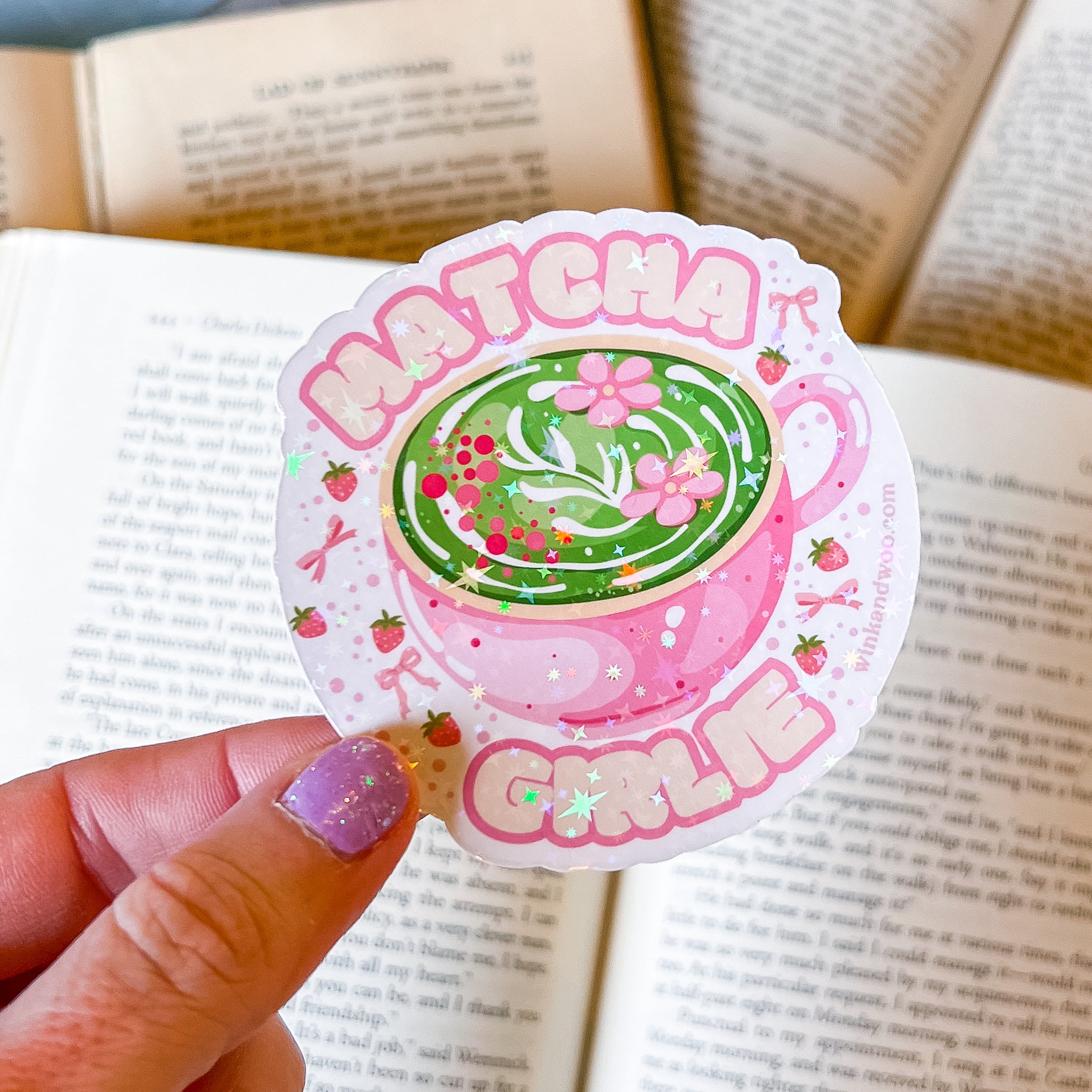 Sticker with a green tea cup design and 'Matcha Girl' text held over an open book.