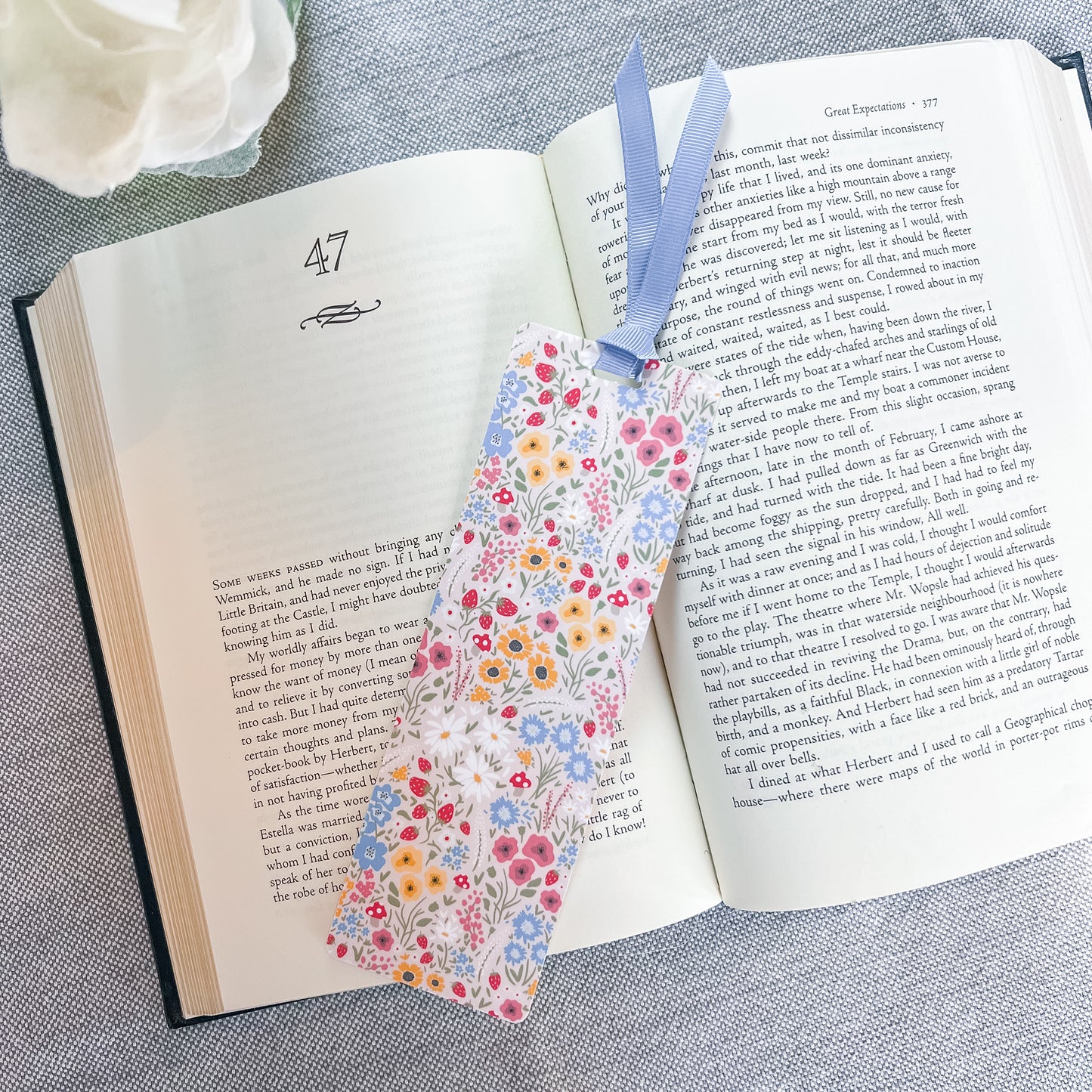 Floral bookmark with a blue ribbon sitting on top of a book