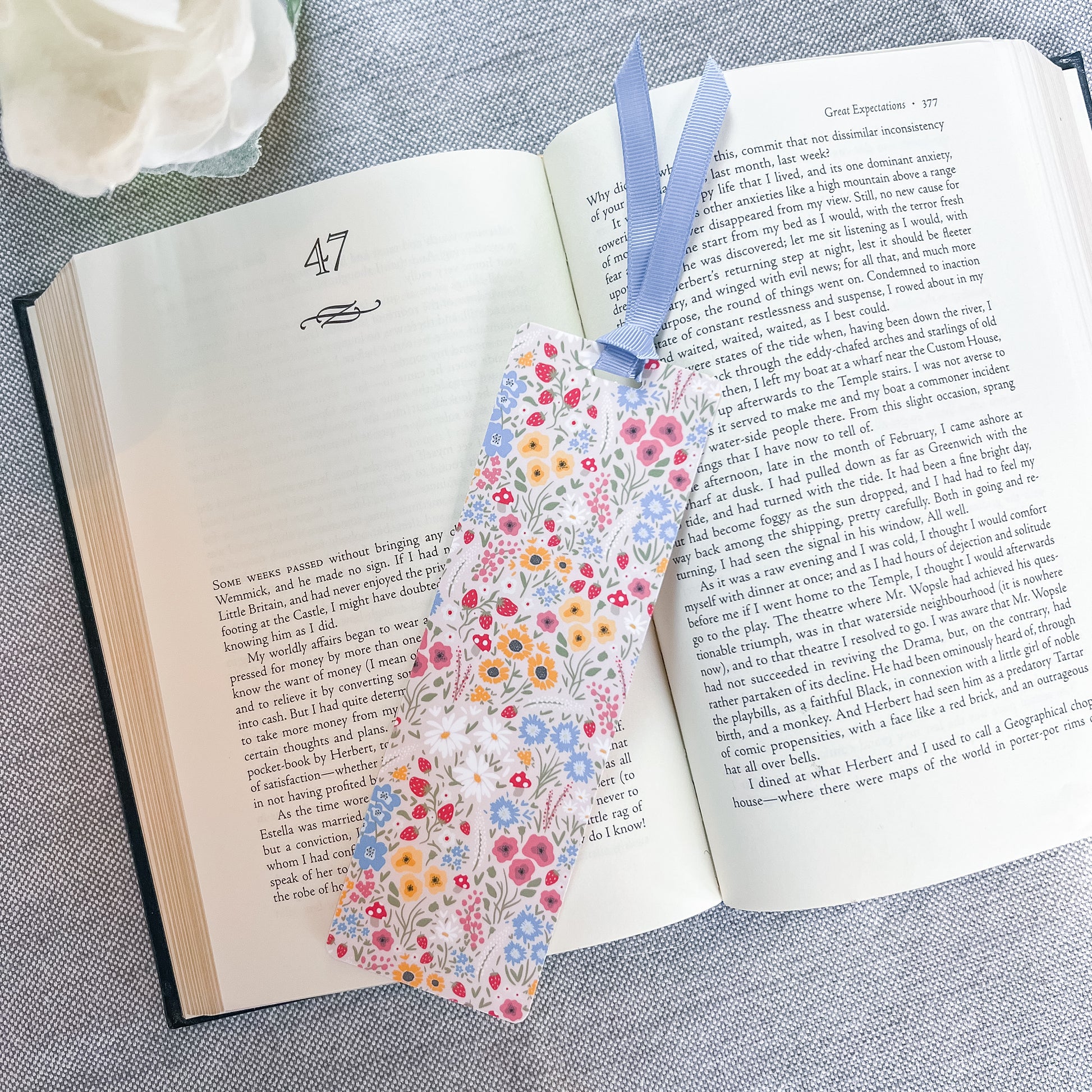 Floral bookmark with a blue ribbon sitting on top of a book