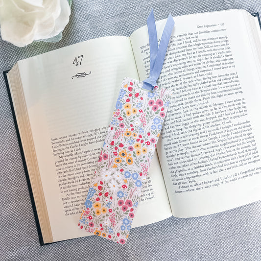 Floral bookmark with a blue ribbon sitting on top of a book