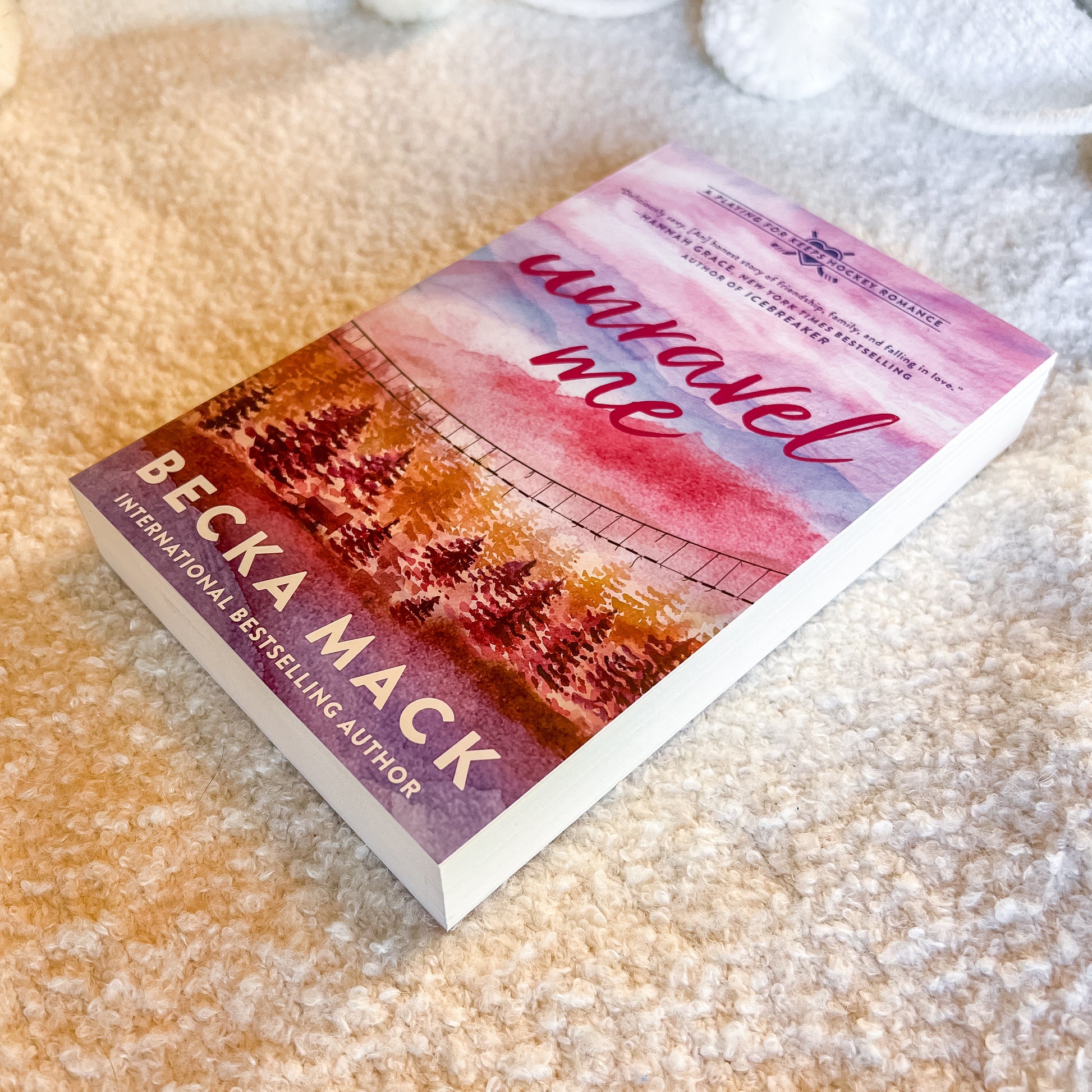 Book titled 'Unravel Me' by Becka Mack on a textured surface