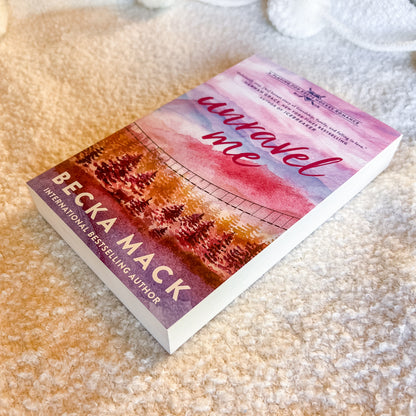 Book titled 'Unravel Me' by Becka Mack on a textured surface