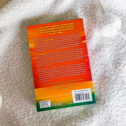 The back cover of the book, featuring a vibrant orange-to-yellow-to-green gradient design with text and a barcode, photographed on a white textured blanket.