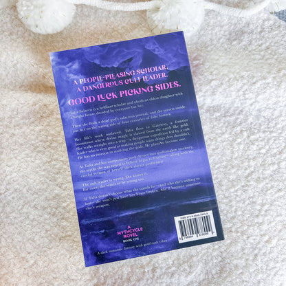 The back cover of a book, featuring a purple and blue textured background with white text, photographed flat on a soft white textured blanket.