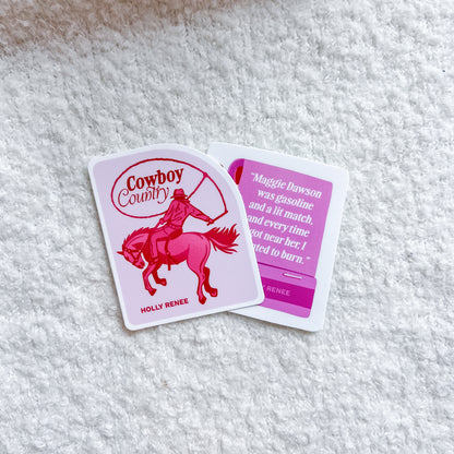 Two printed stickers laid on a white textured fabric background. One card shows a pink cowboy riding a horse with the words 'Cowboy Country' and 'HOLLY RENEE.
