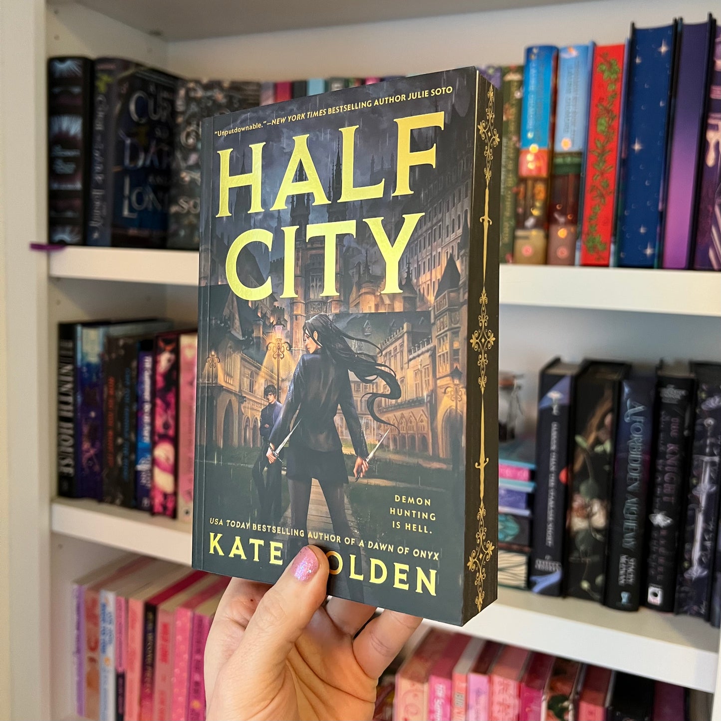 Book titled 'Half City' held in front of a bookshelf with various books.