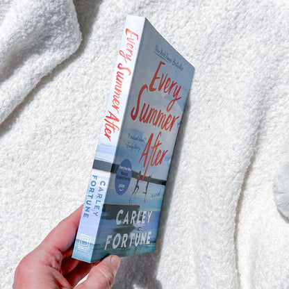 Book titled 'Every Summer After' by Carley Fortune held against a textured white background