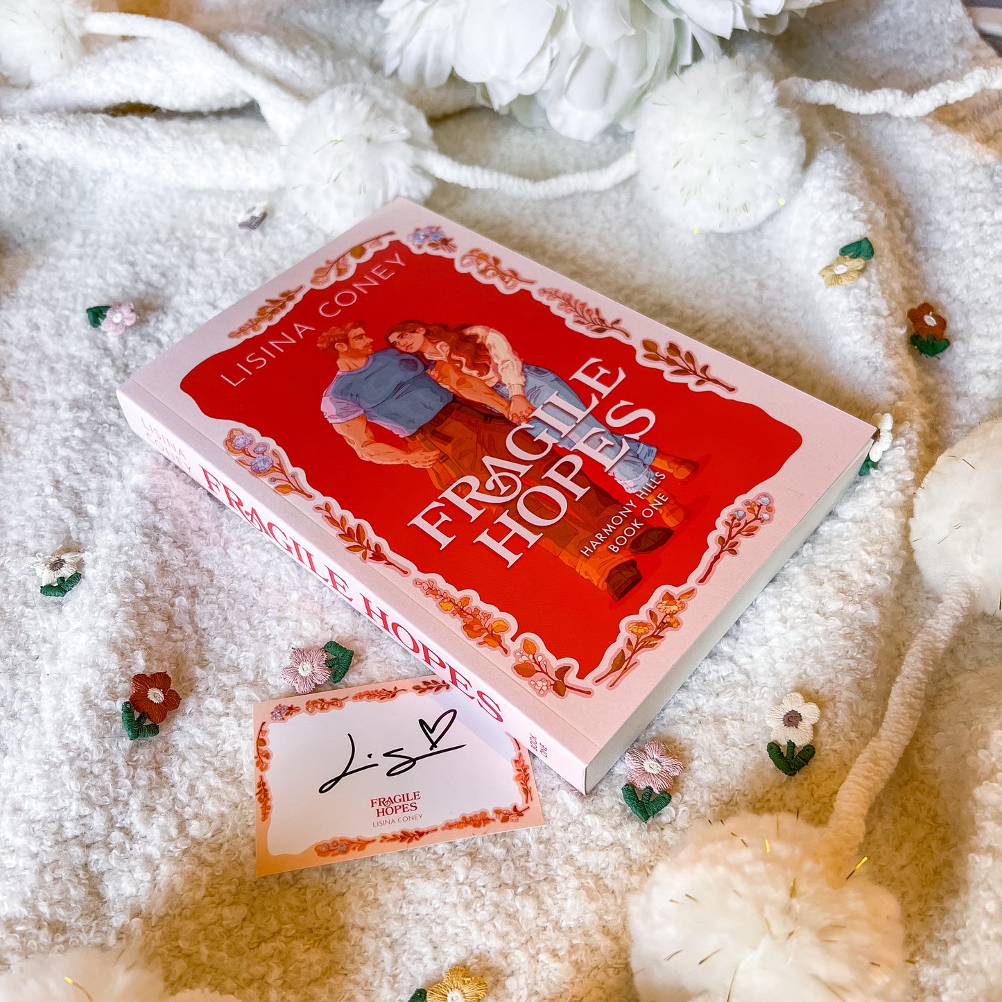 Book titled 'Fragile Heroes' by Lisina Coney on a textured surface with decorative elements.