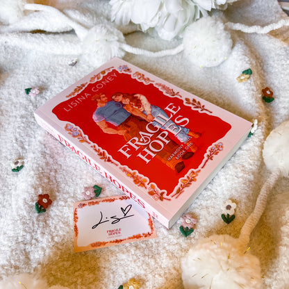 Book titled 'Fragile Heroes' by Lisina Coney on a textured surface with decorative elements.