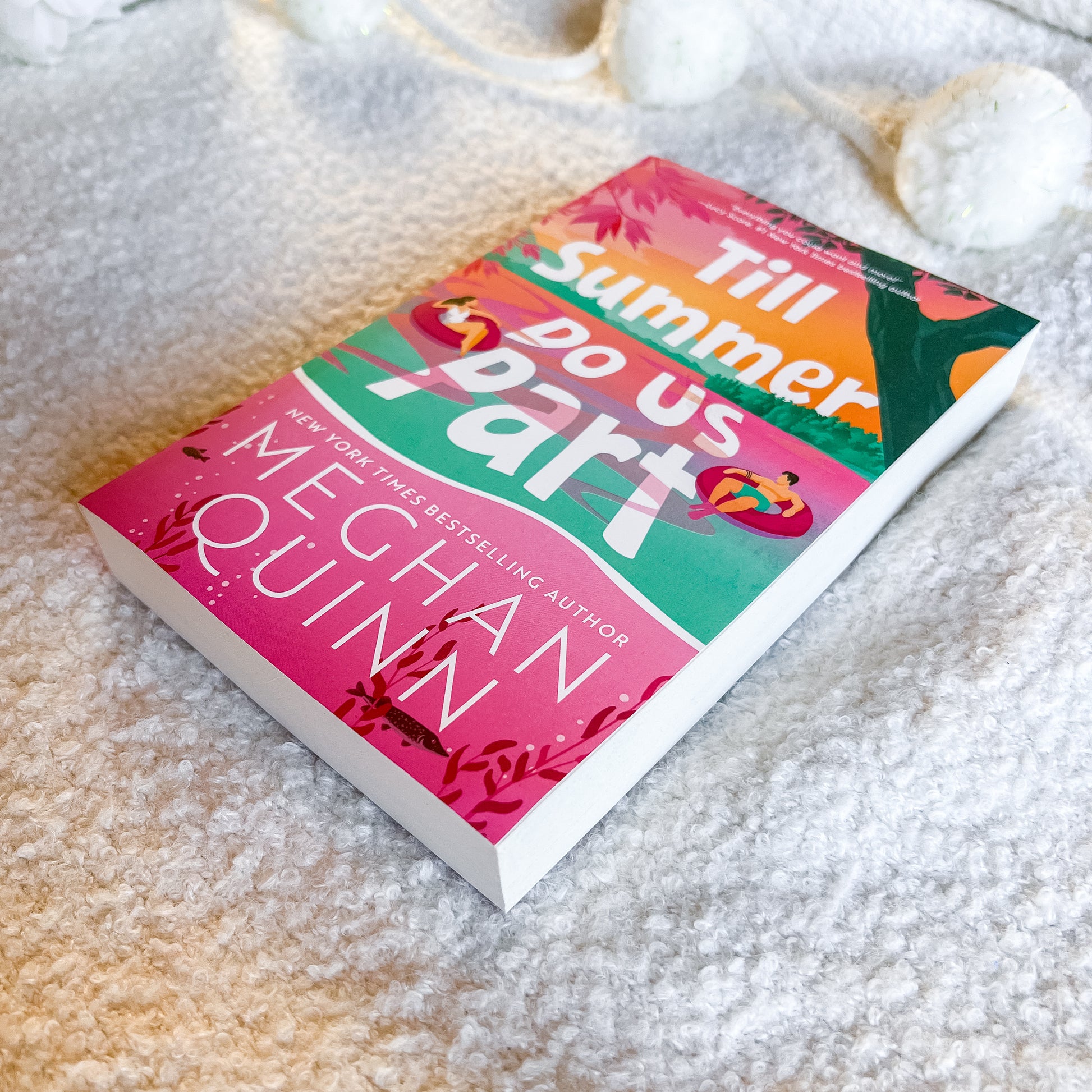 Book titled 'Till Summer Do Us Part' by Meghan Quinn on a sandy surface