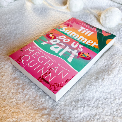 Book titled 'Till Summer Do Us Part' by Meghan Quinn on a sandy surface
