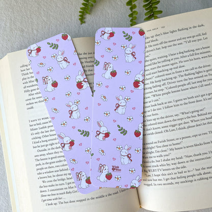 Two pink bookmarks with a bunny design holding berries and flowers.