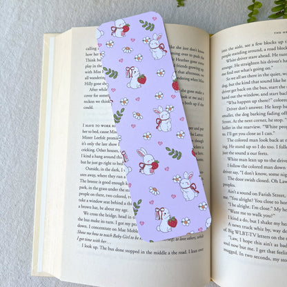 Open book with a pink bookmark with bunny characters holding strawberries and flowers.