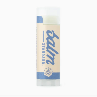 A tube of Standard Balm lip balm with a cream-colored label and blue text and accents, shown on a plain white background.