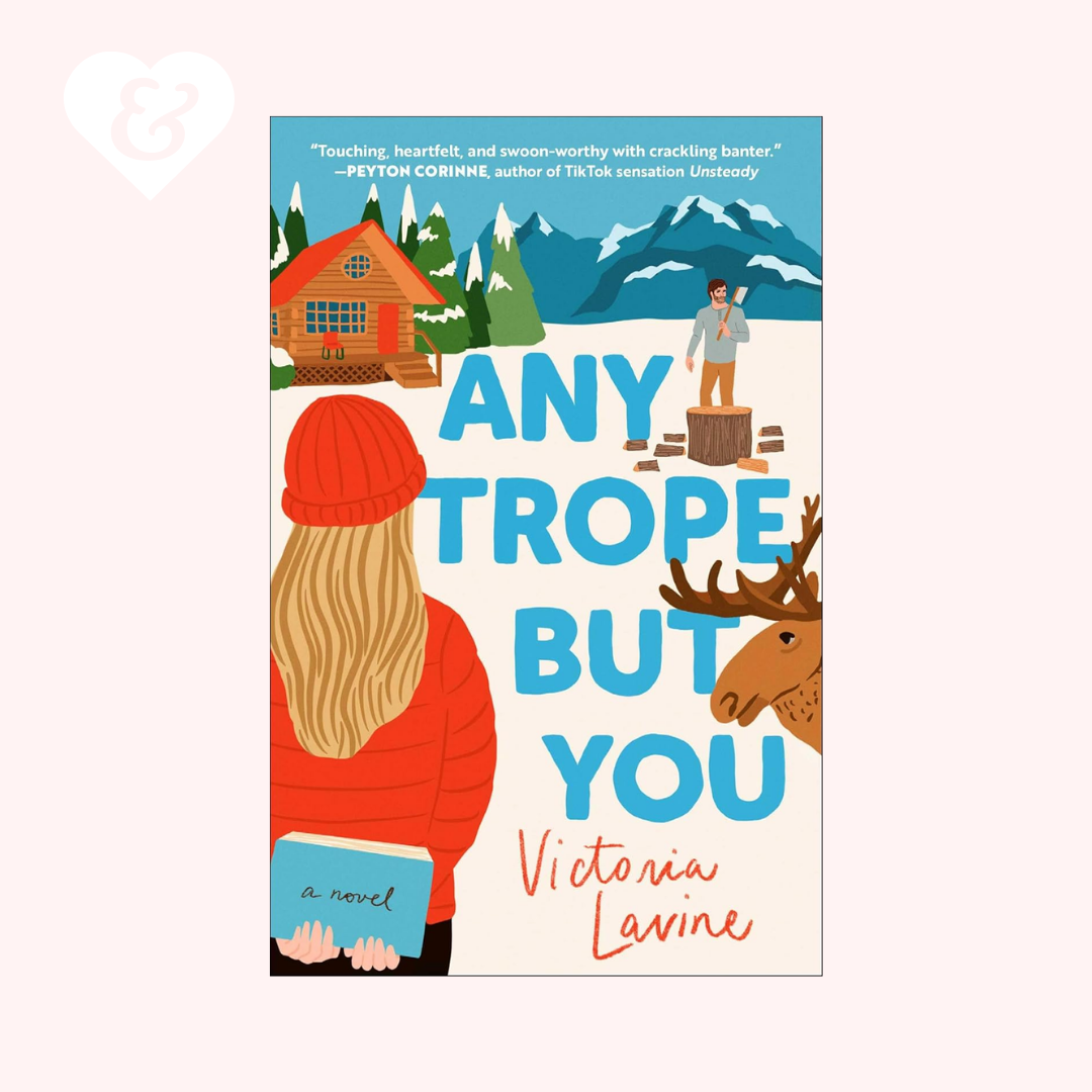 Book cover of 'Any Trope But You' by Victoria Lavine with a woman, cabin, and mountains on a white background