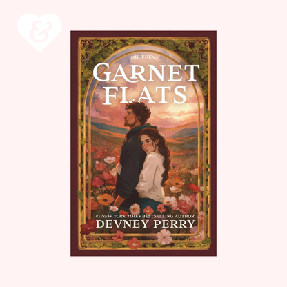 Book cover of 'Garnet Flats' by Devney Perry with a couple in a field and decorative border.