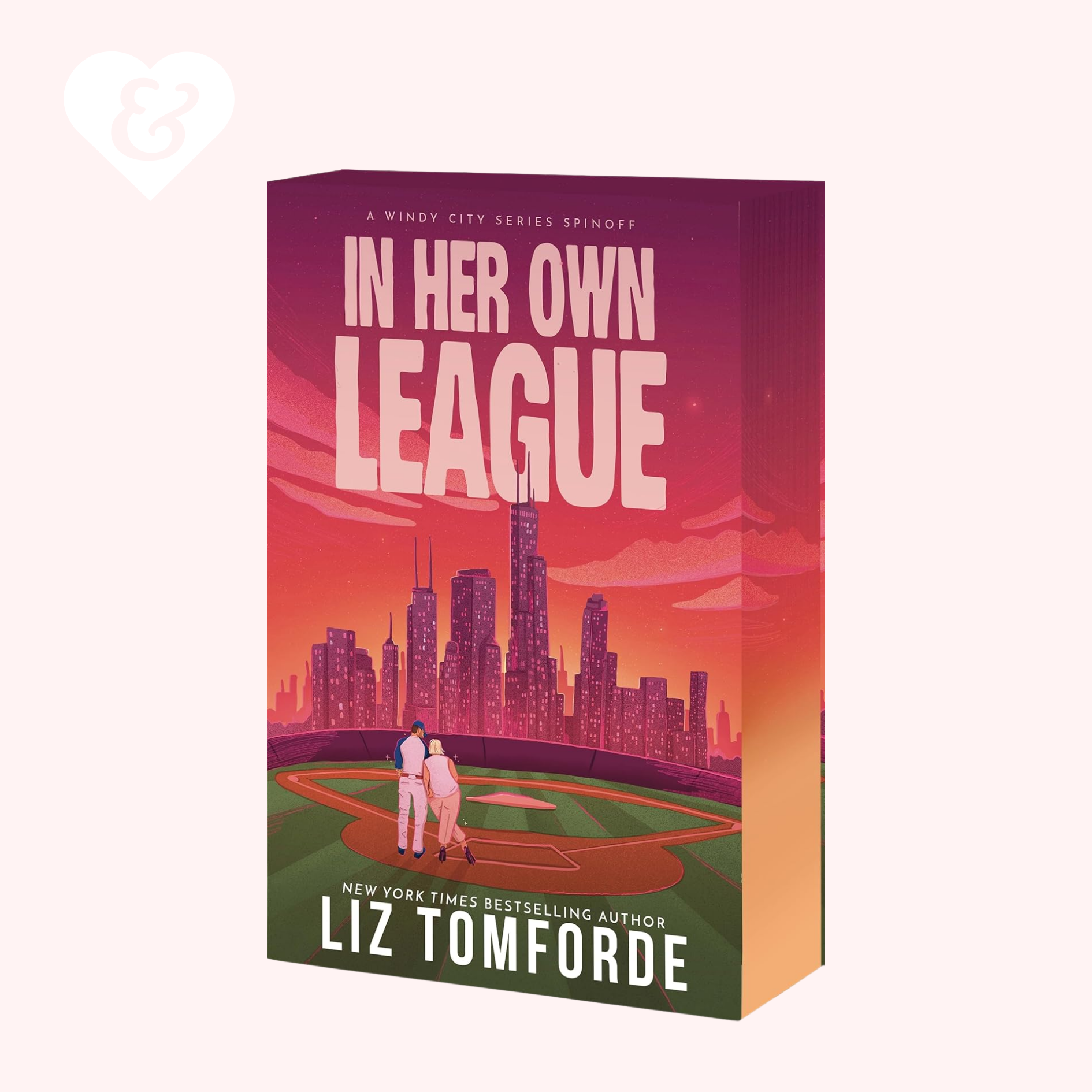 Book cover of 'In Her Own League' by Liz Tomforde with a city skyline and couple on a baseball field.