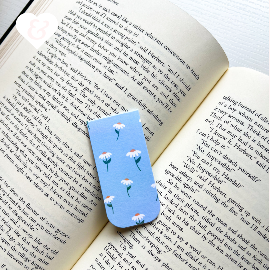 Open book with a blue floral bookmark on a white surface