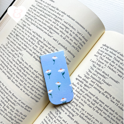 Open book with a blue floral bookmark on a white surface