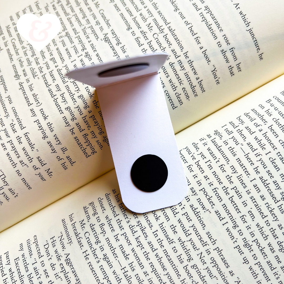 White bookmark with a black magnet on an open book