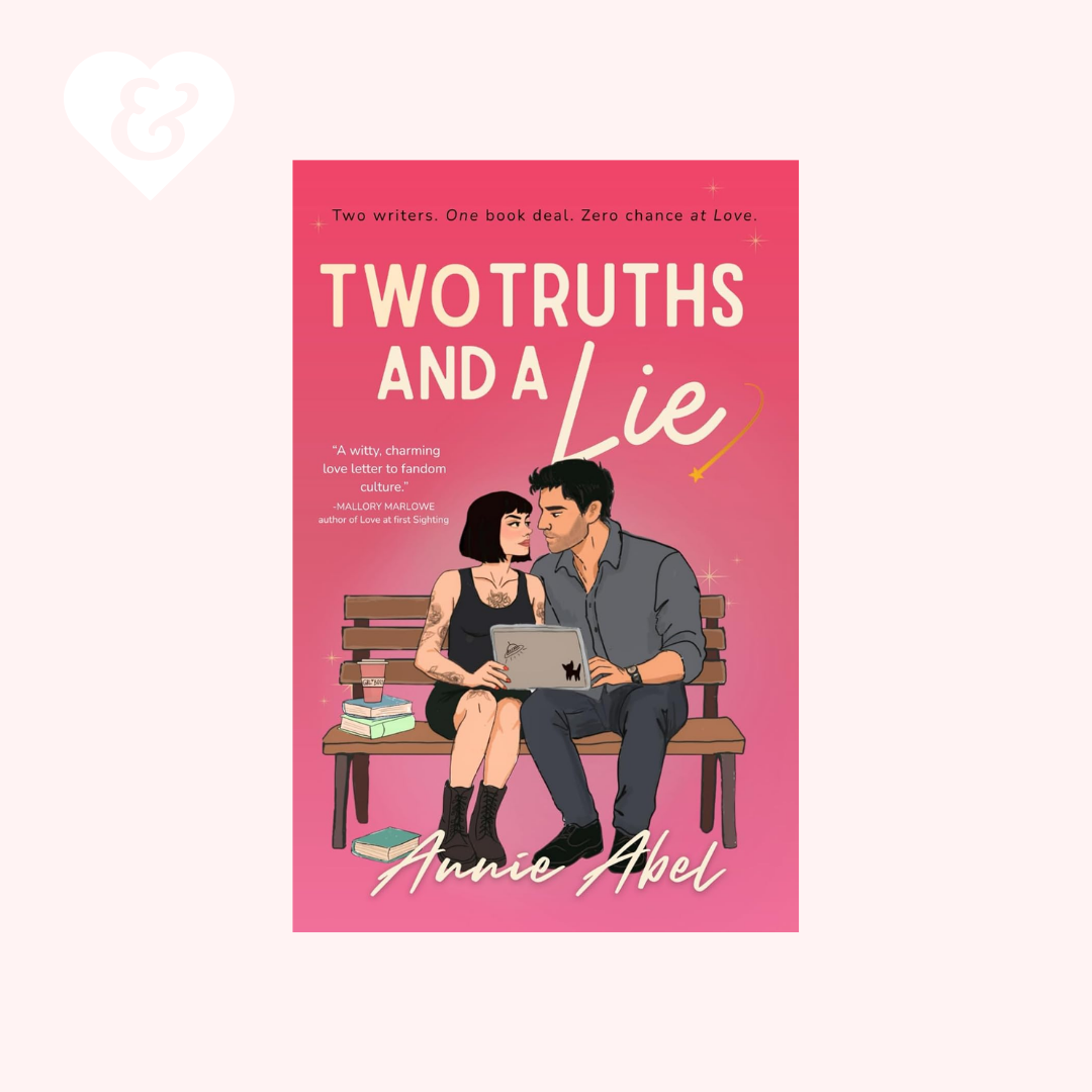 Book cover for 'Two Truths and a Lie' by Annie Abel, featuring a pink background with an illustration of a couple sitting on a bench using a laptop. The book is centered on a pale pink background with a small white heart and ampersand graphic in the top left corner.