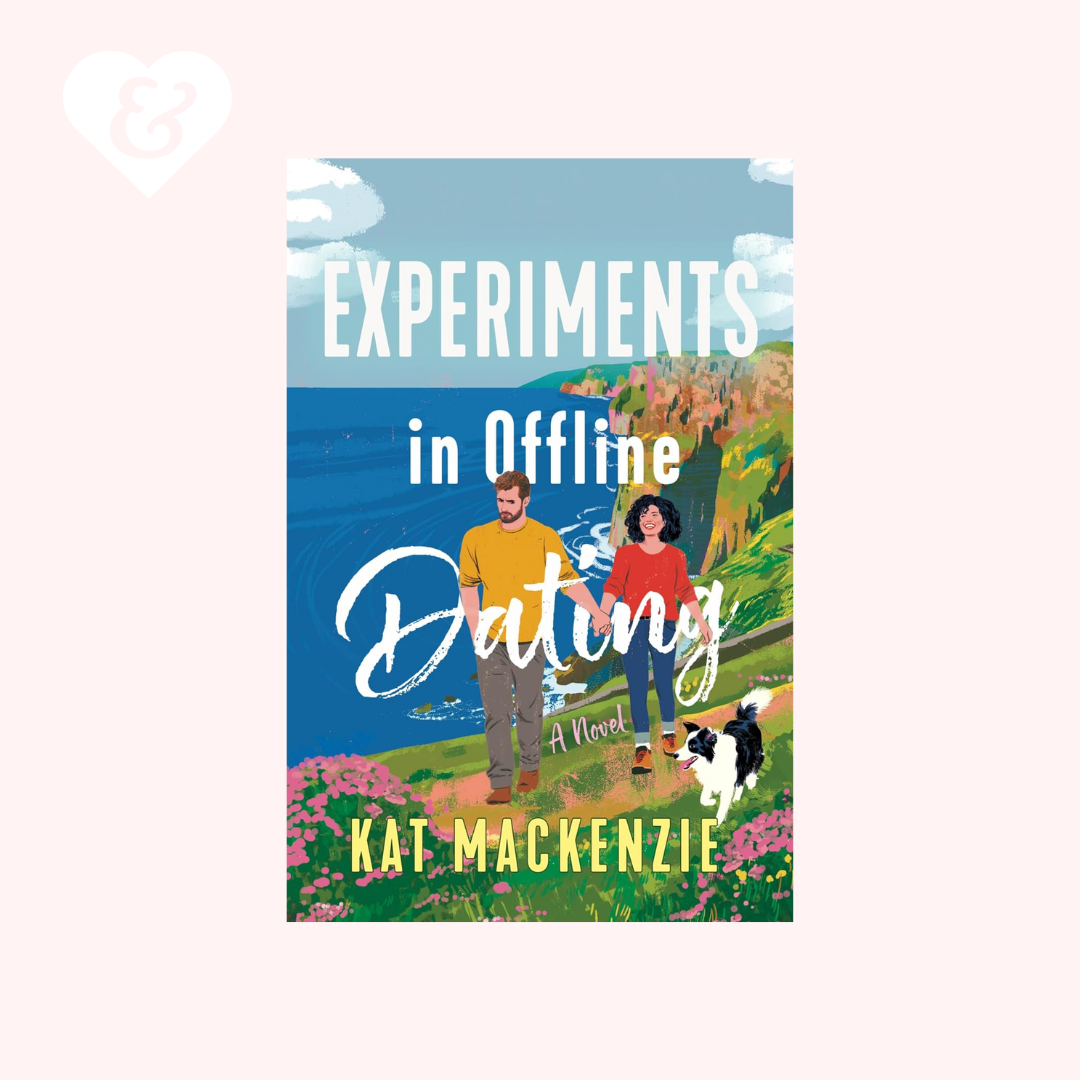 Book cover for 'Experiments in Offline Dating' by Kat Mackenzii, featuring an illustrated couple and dog on a grassy cliffside path with blue ocean and sky in the background, centered on a pale pink background.