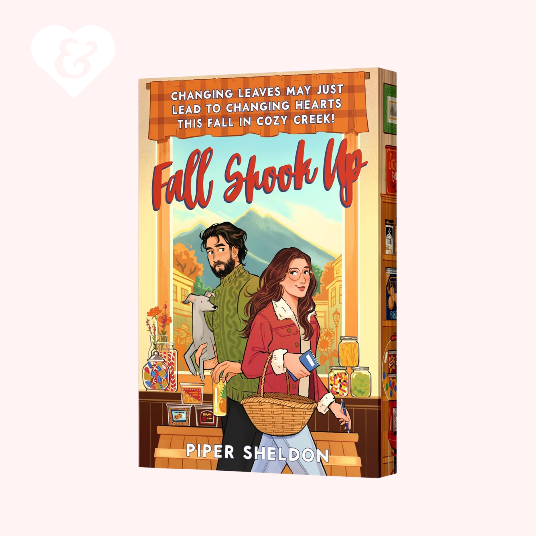 A 3D mockup of a book cover titled 'Fall Shook Up' by Piper Sheldon, featuring an illustrated autumn scene of a couple in a cozy bookstore with a cat, set against a pale pink background.
