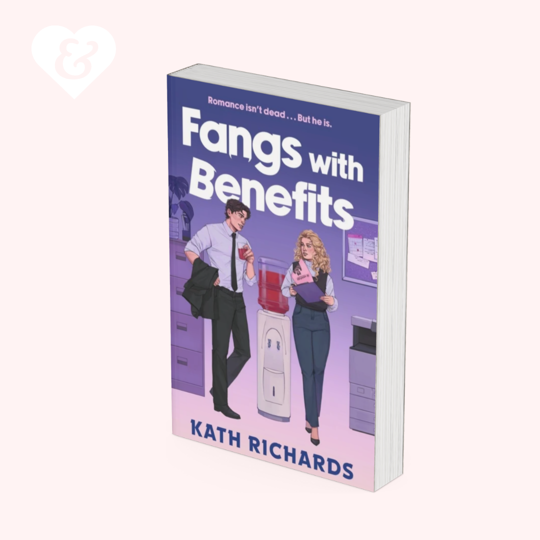 A paperback book titled "Fangs with Benefits" by Kath Richards, shown standing upright at a slight angle. The cover features a purple and pink gradient with an illustration of a man and a woman in an office setting.