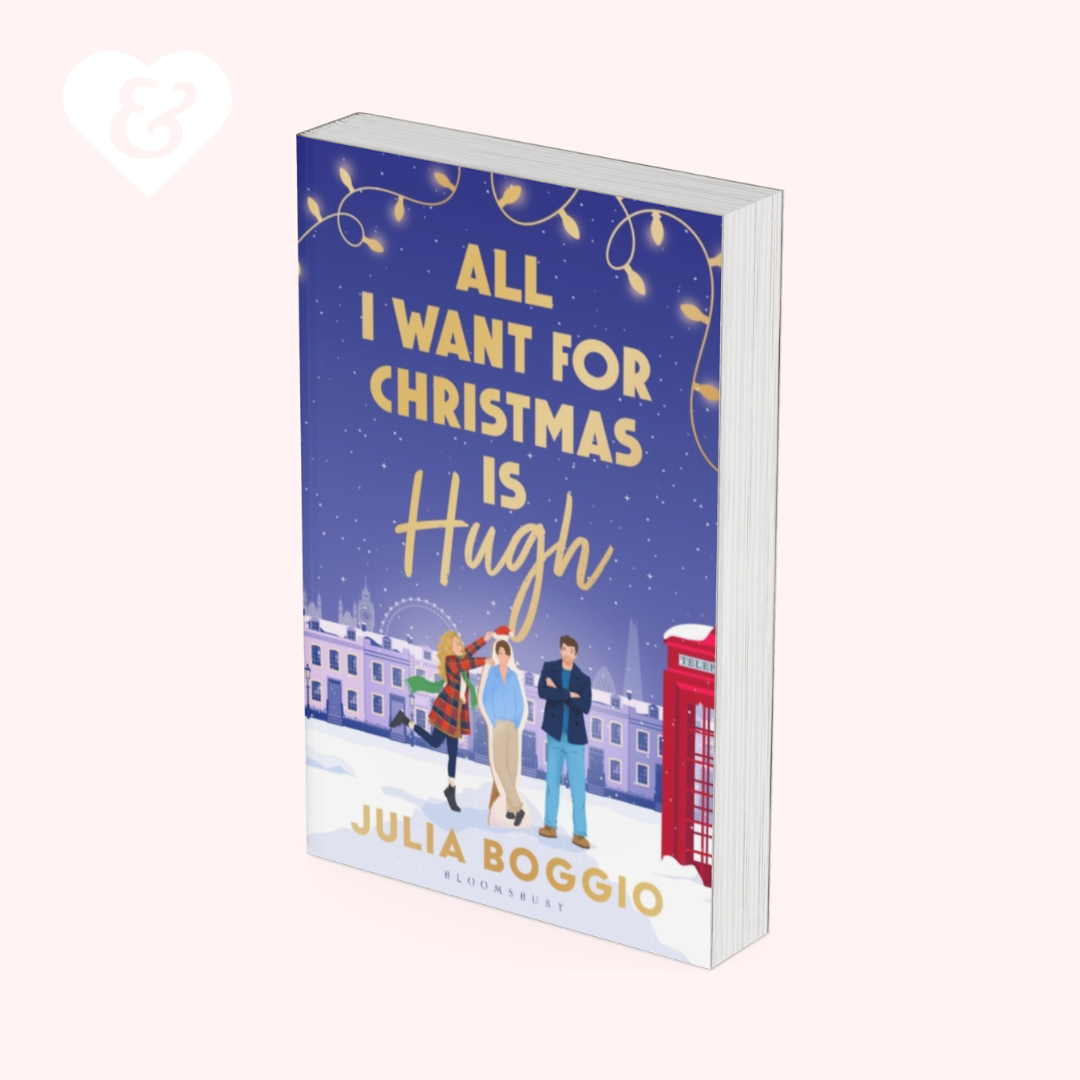 Book cover for 'All I Want For Christmas Is Hugh' by Julia Boggio, featuring a festive blue Christmas night scene with three characters, a red telephone booth, and gold lettering, shown on a light pink background.
