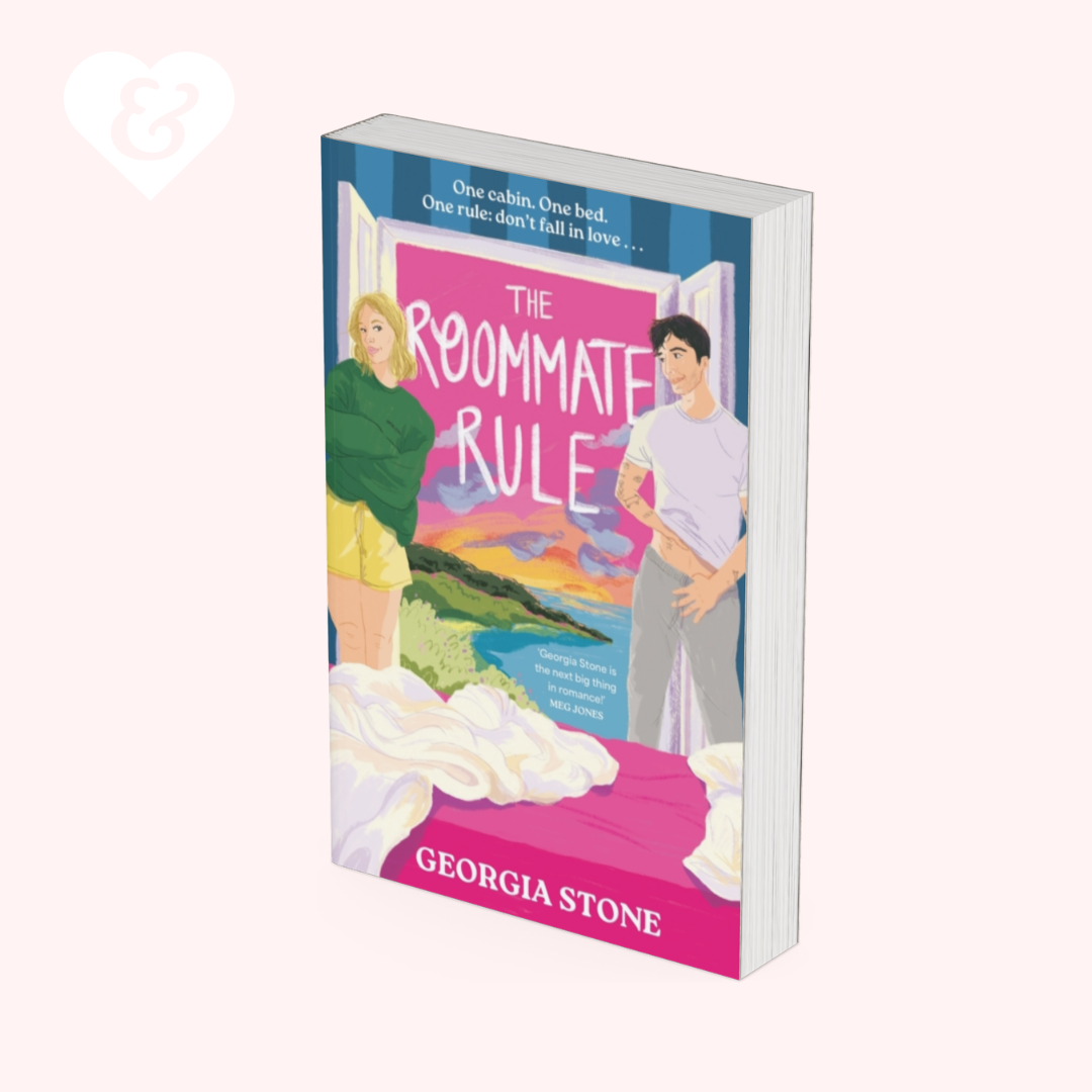 A book cover for 'The Roommate Rule' by Georgia Stone, shown as a 3D mockup on a pale pink background. The cover features an illustration of a blonde woman in a green sweater and yellow shorts, a young man in a white t-shirt and grey pants, and a bright pink bedroom scene with a bed in the foreground.