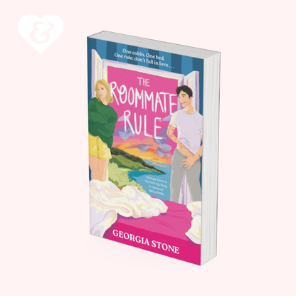 A book cover for 'The Roommate Rule' by Georgia Stone, shown as a 3D mockup on a pale pink background. The cover features an illustration of a blonde woman in a green sweater and yellow shorts, a young man in a white t-shirt and grey pants, and a bright pink bedroom scene with a bed in the foreground.