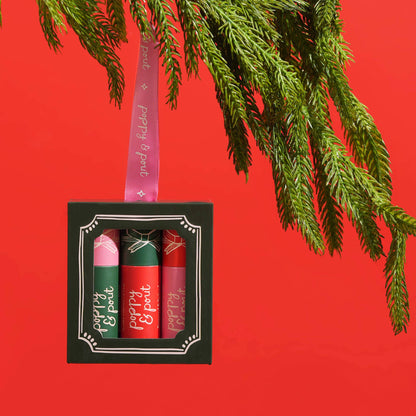Set of lip balms in a decorative box with a pink ribbon on a red background